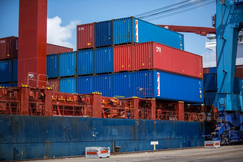 Es sind Container auf einem Containerschiff zu sehen das in einem Containerhafen anliegt.