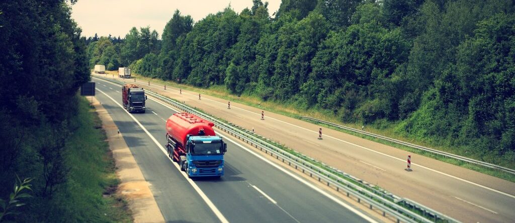 Es ist ein Autobahn Abschnitt zu sehen mit jeweils 2 fahrenden LKWs auf jeder Seite.