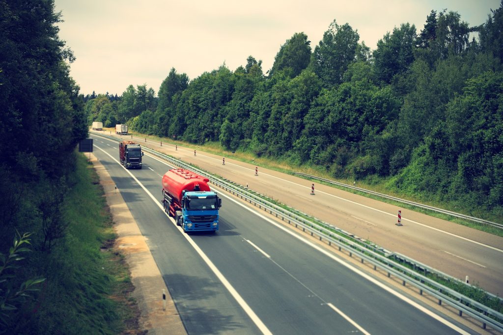 Es ist ein Autobahn Abschnitt zu sehen mit jeweils 2 fahrenden LKWs auf jeder Seite.