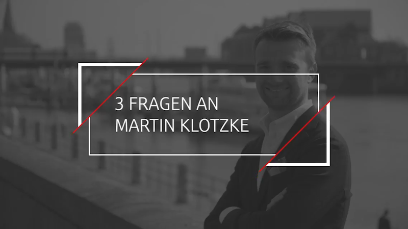 Ein Kasten in der Mitte "3 Fragen an Martin Klotzke" Der Hintergrund ist grau und man sieht einen Mann am Geländer lehnen